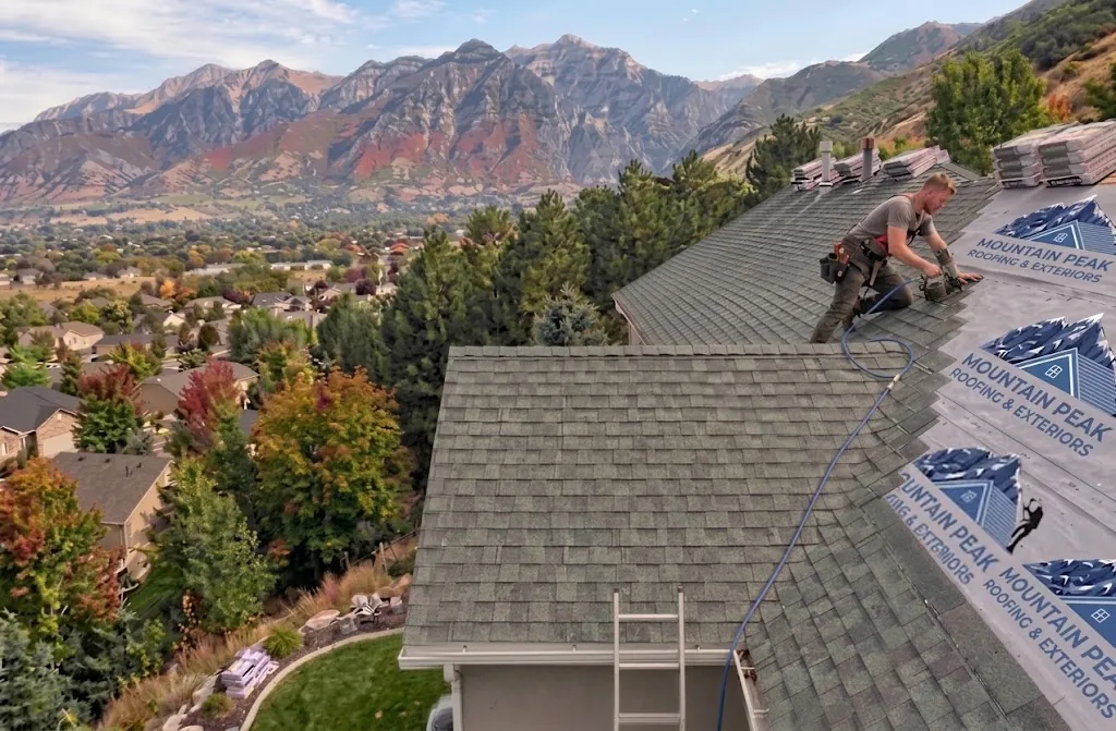 Roofer installing shingles at sunset